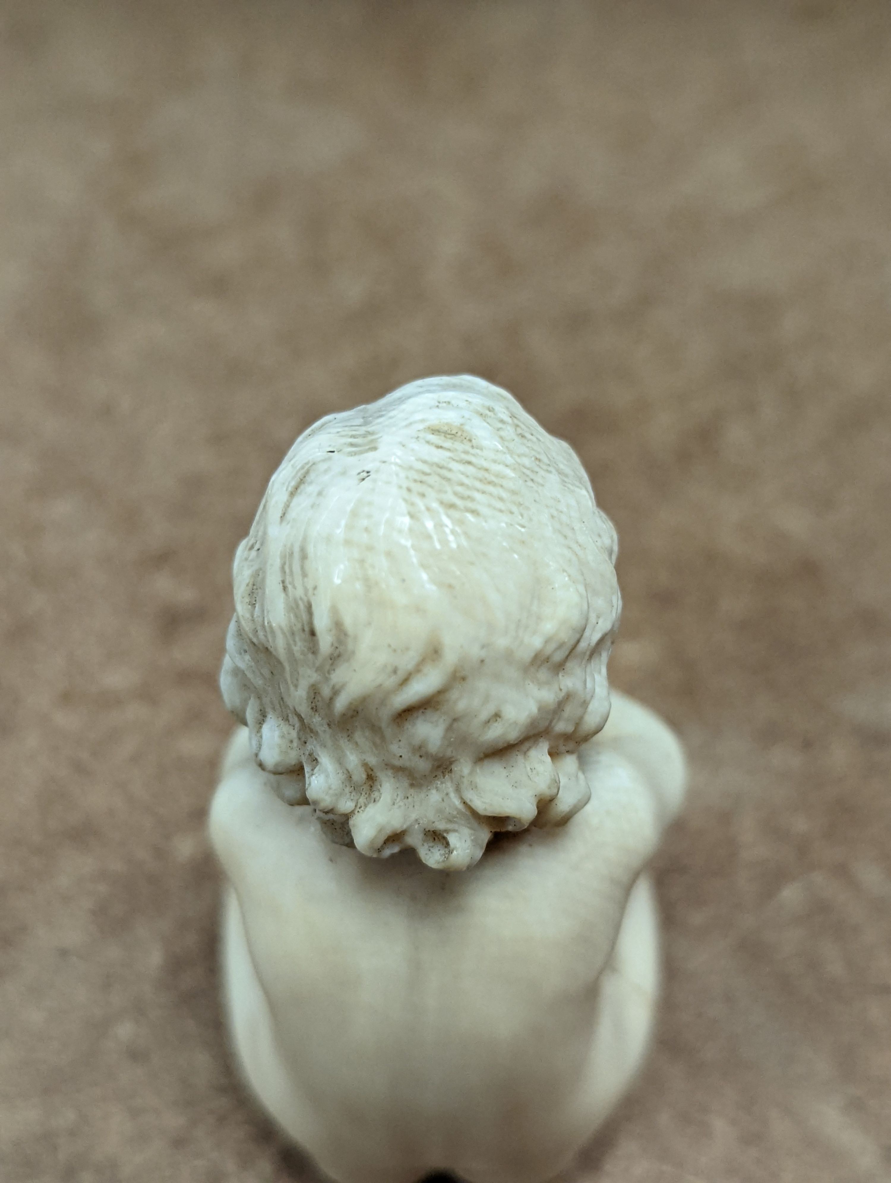 A 19th century Continental carved ivory figure of a child holding a cornucopia - 7cm tall